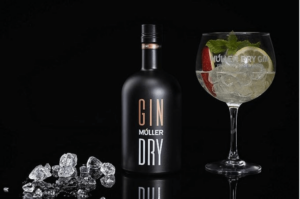 Flasche Gin Müller Dry vor schwarzem Hintergrund neben einem Cocktailglas